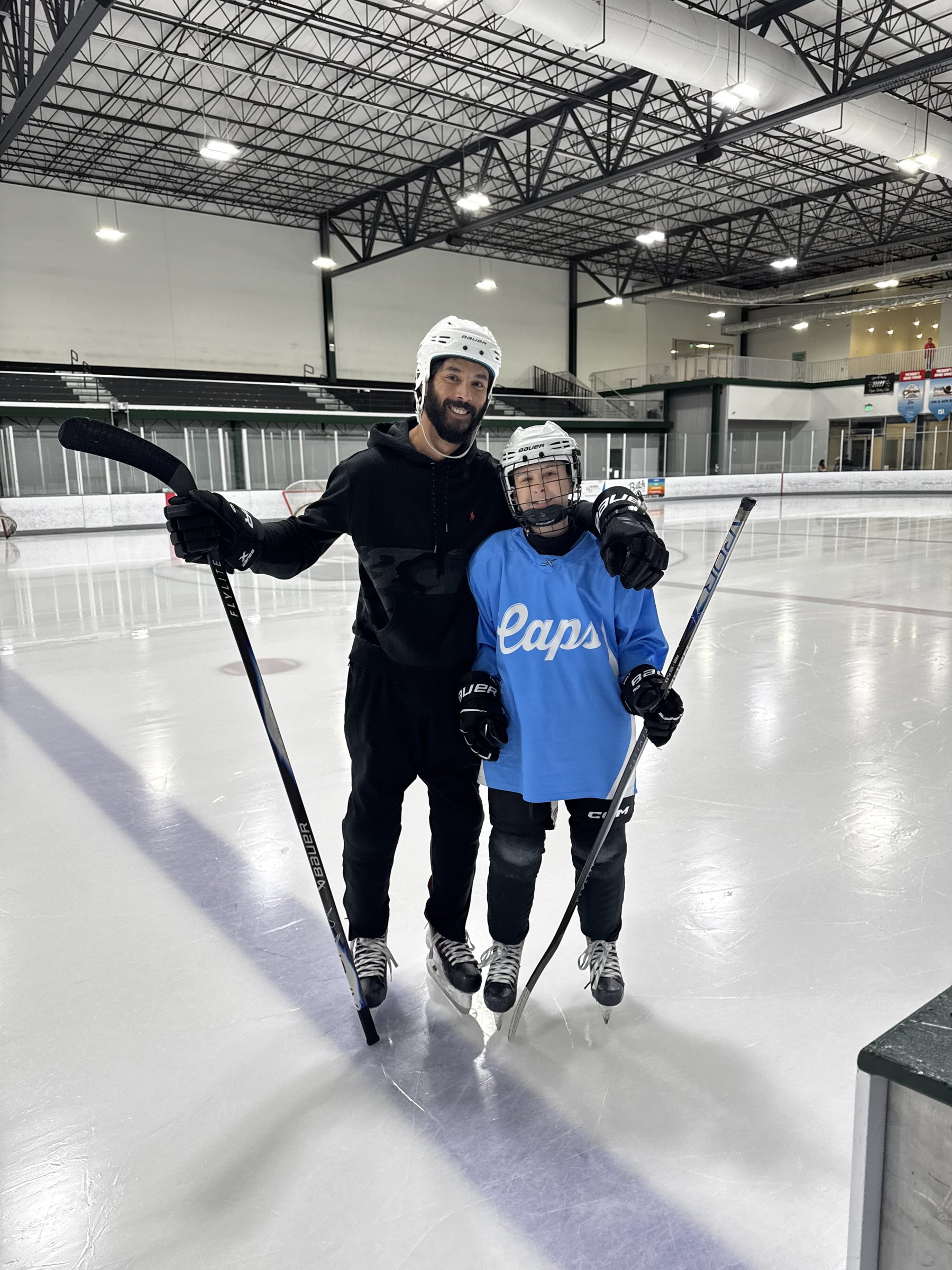 Chris Jeter smiling on the ice with a youth hockey player